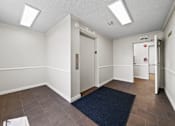 Thumbnail 4 of 10 - A hallway with a blue rug and white walls.