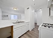 Thumbnail 14 of 18 - A kitchen with a white counter top and a white stove top oven.