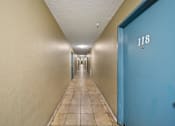 Thumbnail 5 of 18 - A long hallway with a blue door on the right.