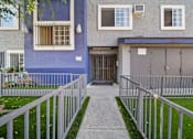 Thumbnail 6 of 10 - A blue building with a white fence and a grey garage door.