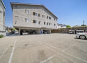 Thumbnail 4 of 10 - A parking lot in front of a concrete building with a car parked in it.
