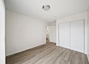 Thumbnail 19 of 38 - A room with a white door and wooden flooring.