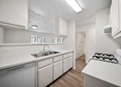 Thumbnail 22 of 38 - A white kitchen with a stove top oven and sink.