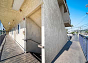 Thumbnail 4 of 14 - A long concrete building with a wooden walkway in front.