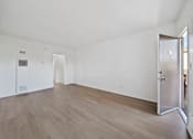 Thumbnail 17 of 20 - A room with a wooden floor and white walls.