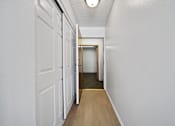Thumbnail 10 of 33 - A long hallway with white walls and wood flooring.