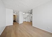Thumbnail 15 of 33 - A white room with wooden flooring and a doorway leading to another room.