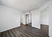 Thumbnail 26 of 33 - A room with white walls and wood flooring with a doorway leading to another room.