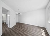Thumbnail 11 of 33 - A room with a wooden floor and white walls.