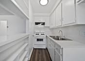 Thumbnail 29 of 30 - A modern kitchen with white cabinets and a wooden floor.