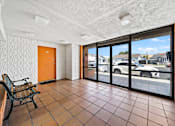 Thumbnail 8 of 30 - A room with a tiled floor and a view of a parking lot through the windows.