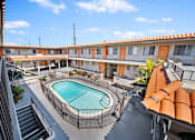 Thumbnail 11 of 30 - A pool in a courtyard surrounded by orange buildings.