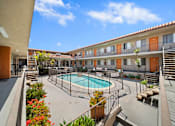 Thumbnail 13 of 30 - A pool surrounded by a fence and a building with orange doors.