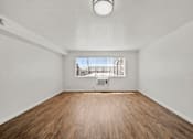 Thumbnail 11 of 29 - Empty room with wooden floor and white walls.