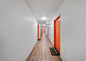 Thumbnail 15 of 29 - A long hallway with orange doors and a black doormat.