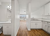 Thumbnail 21 of 29 - A white bathroom with a wooden floor and white cabinets.