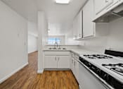 Thumbnail 22 of 29 - A kitchen with a stove, sink, and cabinets.