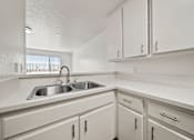 Thumbnail 25 of 29 - A white kitchen with a sink and cabinets.