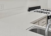 Thumbnail 26 of 29 - A black and white photo of a kitchen with a stove and sink.