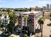 Thumbnail 3 of 29 - A building with a red and white striped facade is surrounded by palm trees.