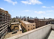 Thumbnail 6 of 29 - A cityscape is visible in the distance from a rooftop view.