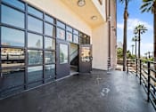 Thumbnail 7 of 29 - The image shows a building entrance with a glass door and a sign above it.