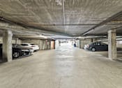 Thumbnail 8 of 29 - A parking garage with cars parked on both sides of the aisle.