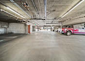 Thumbnail 9 of 29 - A red car is parked in a large, empty parking garage.