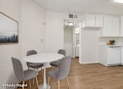 Thumbnail 4 of 21 - A white dining table with grey chairs in a white kitchen.