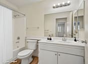 Thumbnail 4 of 17 - A white bathroom with a toilet, sink, mirror and tub.