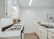 Thumbnail 3 of 17 - A kitchen with a stove top oven, a sink and plenty of storage