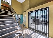 Thumbnail 7 of 17 - A staircase with a metal railing leads to a black gate.
