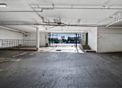 Thumbnail 9 of 17 - A large, empty parking garage with a view of the city through the open door.