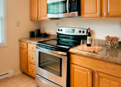 Thumbnail 3 of 22 - A kitchen with a stove top oven and microwave above it at Rivercrest Apartments, Piscataway , NJ