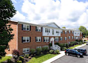 Thumbnail 4 of 11 - A row of townhouses with a car parked in front at Kings Gate West Apartments, Camillus 13031