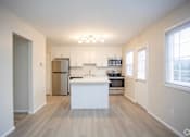 Thumbnail 7 of 11 - A kitchen with a white island and stainless steel appliances at Kings Gate West Apartments, Camillus