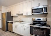 Thumbnail 6 of 11 - A kitchen with white cabinets and black appliances at Kings Gate West Apartments, Camillus, New York