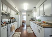 Thumbnail 30 of 48 - A kitchen with white cabinets and a wooden floor.