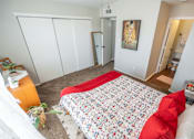 Thumbnail 35 of 48 - A bedroom with a bed, a dresser, and a mirror.
