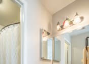 Thumbnail 31 of 48 - A bathroom with a sink, mirror, and shower curtain.