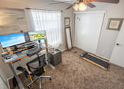 Thumbnail 38 of 48 - A room with a desk, chair, and a treadmill.