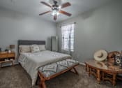 Thumbnail 41 of 48 - A bedroom with a bed, a table, and a ceiling fan.