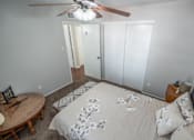Thumbnail 48 of 48 - A bedroom with a bed, a ceiling fan, and a small table.