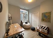 Thumbnail 11 of 45 - A room with a wooden table, a bean bag chair, and a painting on the wall.