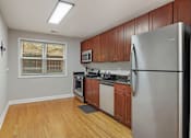 Thumbnail 22 of 31 - A kitchen with wooden cabinets and a stainless steel refrigerator.