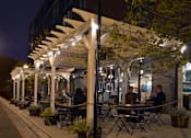 Thumbnail 21 of 31 - A restaurant with tables and chairs under a canopy with lights.