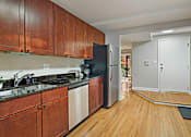 Thumbnail 24 of 31 - A kitchen with wooden cabinets and a black fridge.