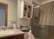 Thumbnail 12 of 13 - A bathroom with a toilet, sink, and shower.
