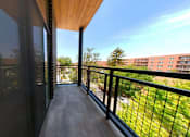 Thumbnail 15 of 61 - A balcony with a black railing and a view of a building across the way.