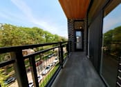 Thumbnail 16 of 61 - A balcony with a view of a parking lot and trees.